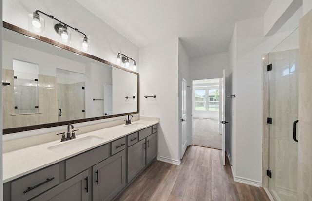 full bathroom featuring double vanity, a sink, a shower stall, and wood finished floors