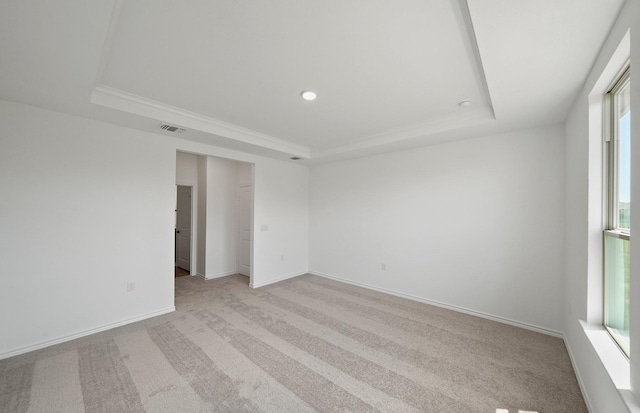 unfurnished room with baseboards, a raised ceiling, visible vents, and light colored carpet