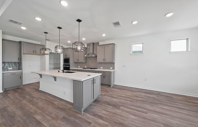 kitchen featuring gas cooktop, wall chimney range hood, gray cabinets, and visible vents