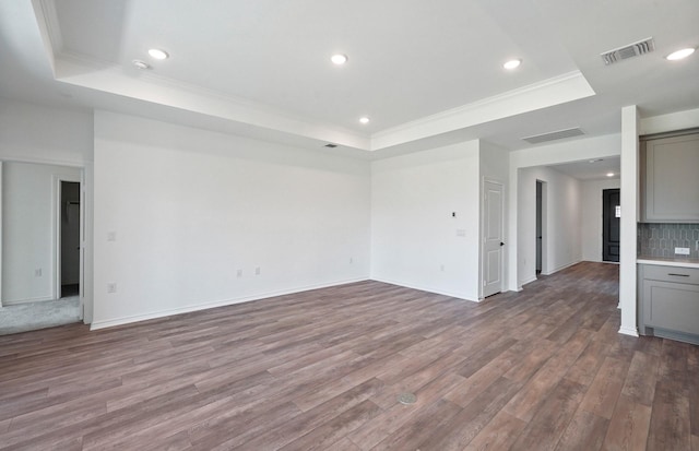 unfurnished living room featuring visible vents, a tray ceiling, and wood finished floors