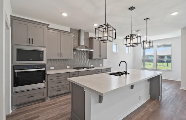 kitchen with gas stovetop, gray cabinetry, a sink, stainless steel oven, and wall chimney range hood