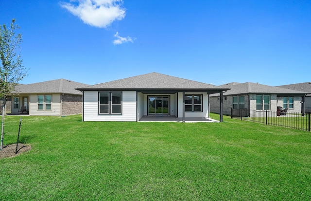 rear view of property with a shingled roof, a patio area, fence, and a lawn