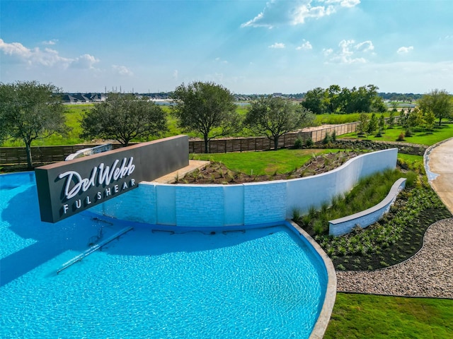 view of swimming pool with a yard and fence