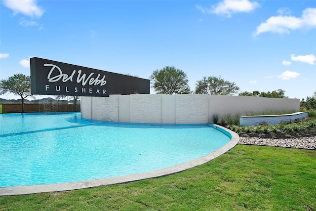 view of swimming pool featuring an infinity pool, fence, and a yard