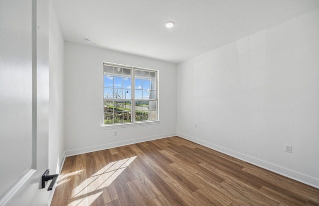 spare room with baseboards and wood finished floors