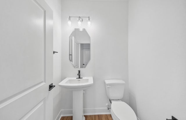 bathroom with baseboards, a sink, toilet, and wood finished floors