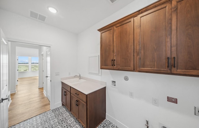 clothes washing area featuring hookup for a gas dryer, visible vents, cabinet space, a sink, and electric dryer hookup