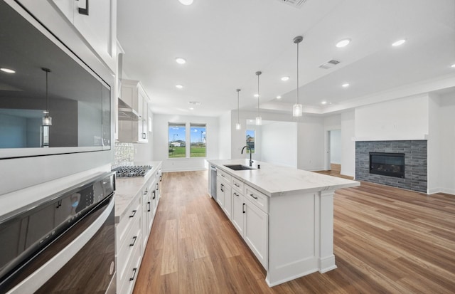 kitchen featuring visible vents, white cabinets, light wood-style flooring, stainless steel appliances, and a sink