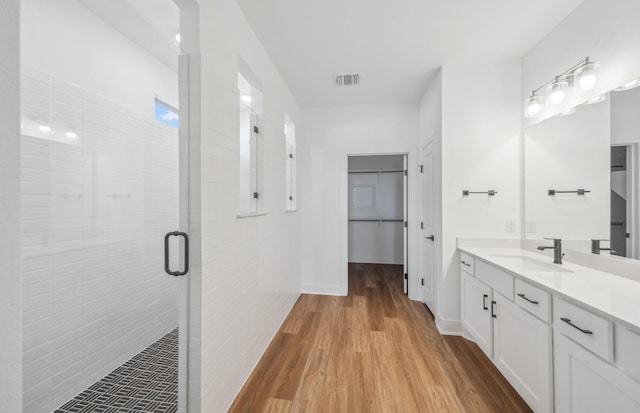 bathroom with a stall shower, baseboards, visible vents, wood finished floors, and vanity