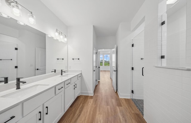 full bath featuring double vanity, wood finished floors, a sink, and a shower stall