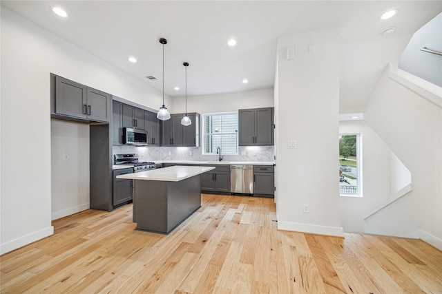 kitchen with appliances with stainless steel finishes, a center island, decorative light fixtures, light countertops, and backsplash