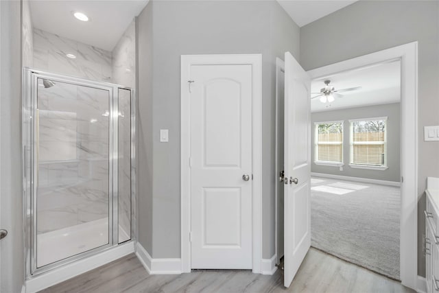 full bathroom featuring baseboards, vanity, a marble finish shower, and wood finished floors