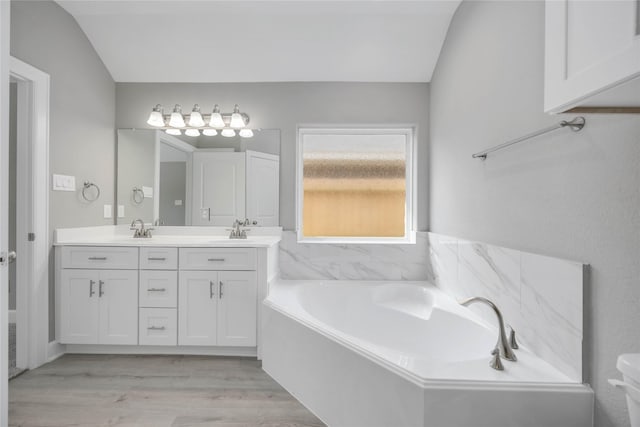 bathroom with a sink, double vanity, wood finished floors, and a garden tub