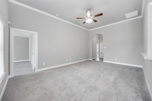 spare room with light carpet, visible vents, arched walkways, and ornamental molding