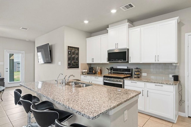 kitchen featuring stainless steel appliances, a sink, a center island with sink, and white cabinetry