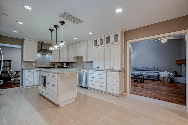 kitchen with decorative light fixtures, visible vents, glass insert cabinets, white cabinetry, and wall chimney range hood