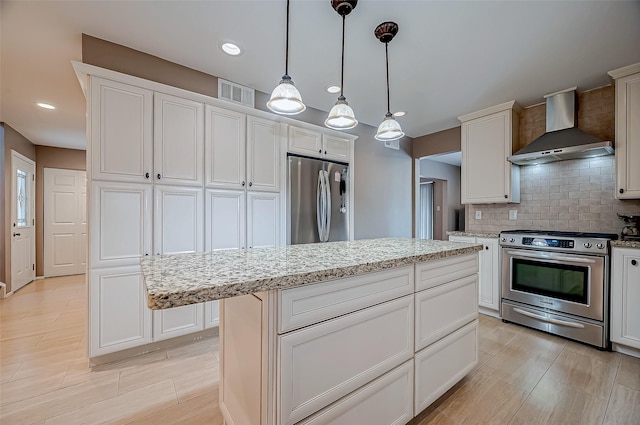 kitchen featuring a kitchen island, appliances with stainless steel finishes, hanging light fixtures, wall chimney range hood, and backsplash