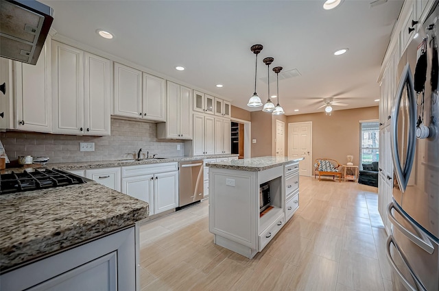 kitchen with a kitchen island, white cabinets, hanging light fixtures, appliances with stainless steel finishes, and glass insert cabinets