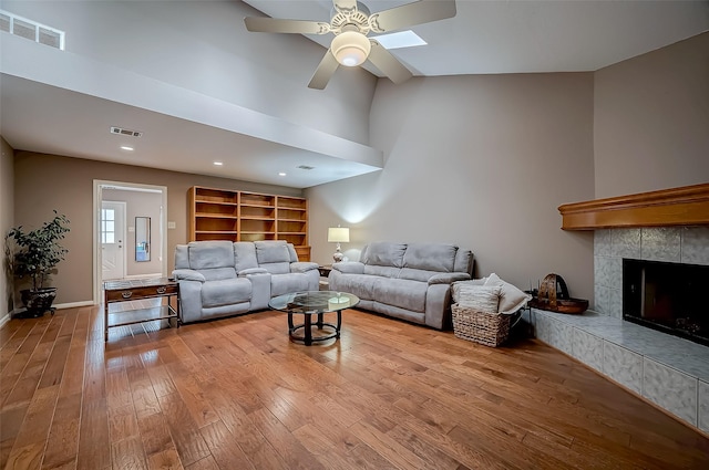 living room featuring a ceiling fan, light wood-type flooring, visible vents, and a fireplace