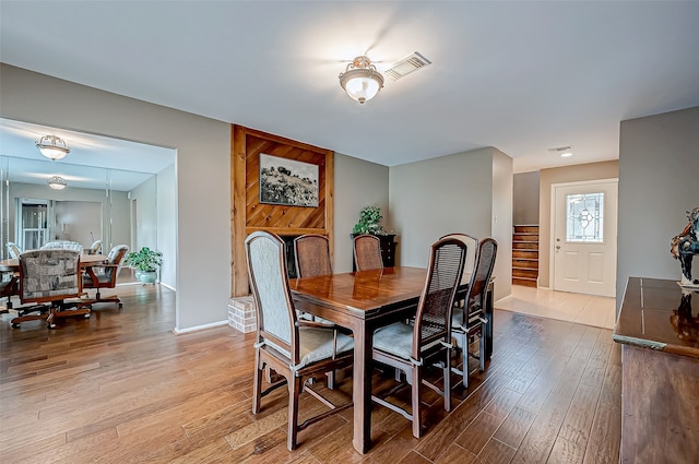 dining area featuring light wood-type flooring, visible vents, baseboards, and stairs