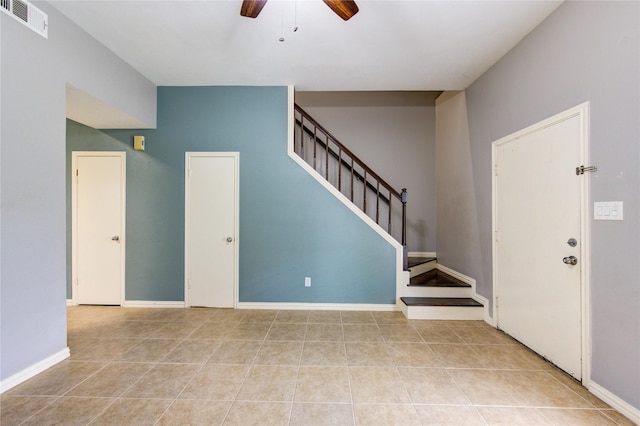 entryway with visible vents, a ceiling fan, light tile patterned flooring, baseboards, and stairs