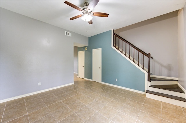 empty room featuring baseboards, visible vents, a ceiling fan, stairway, and light tile patterned flooring