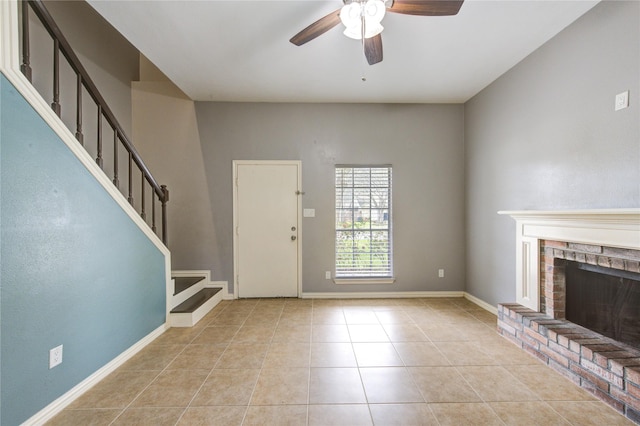 foyer with a fireplace, a ceiling fan, light tile patterned flooring, baseboards, and stairs