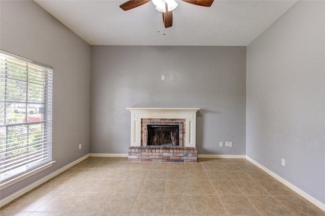 unfurnished living room featuring ceiling fan, a brick fireplace, light tile patterned flooring, and baseboards