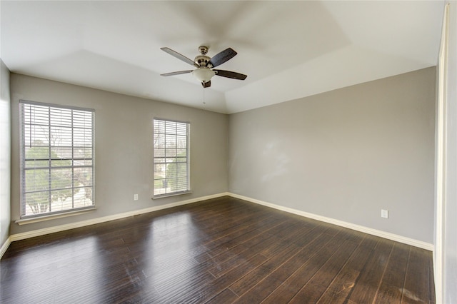 unfurnished room with dark wood-style flooring, a ceiling fan, and baseboards