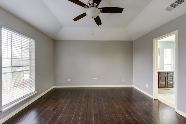 unfurnished room featuring lofted ceiling, baseboards, visible vents, and dark wood-type flooring