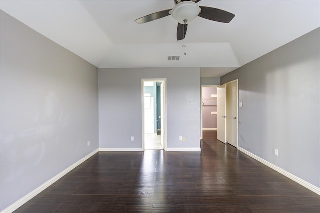 empty room with a ceiling fan, dark wood-style flooring, visible vents, and baseboards