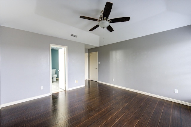 spare room with dark wood-type flooring, visible vents, ceiling fan, and baseboards