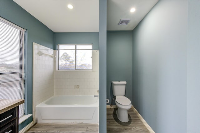 full bath with toilet, a garden tub, wood finished floors, and visible vents