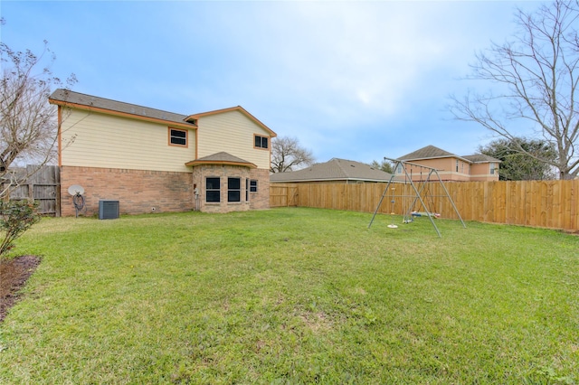 back of house featuring a yard, a fenced backyard, a playground, and brick siding