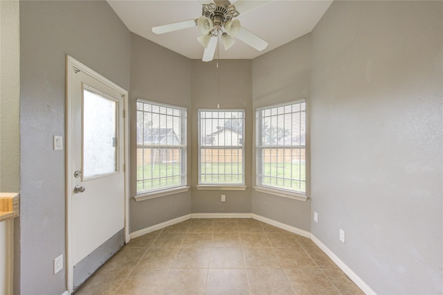 empty room featuring light tile patterned floors, baseboards, and a ceiling fan