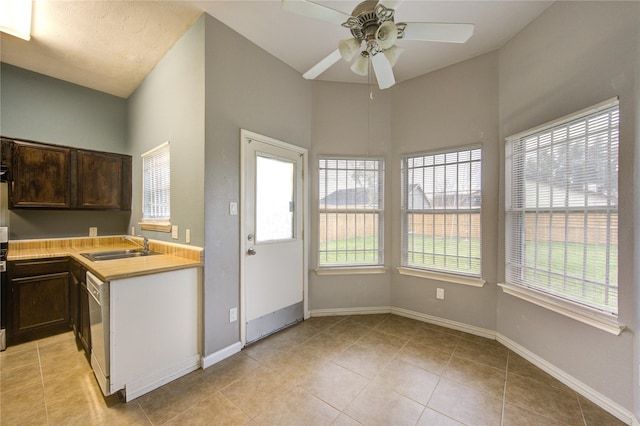 kitchen with dishwashing machine, light countertops, a sink, dark brown cabinetry, and baseboards