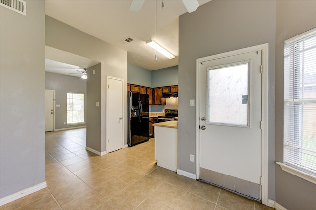 kitchen with brown cabinets, stainless steel electric stove, light countertops, black fridge with ice dispenser, and visible vents