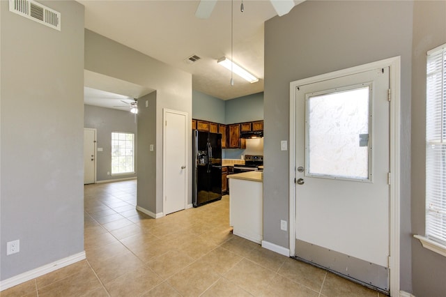 kitchen with electric range, visible vents, brown cabinets, light countertops, and black fridge