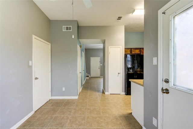 hall with light tile patterned floors, baseboards, and visible vents