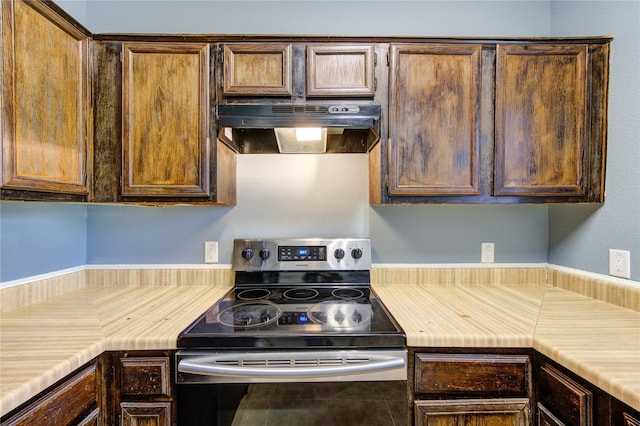 kitchen featuring light countertops, ventilation hood, and stainless steel range with electric stovetop