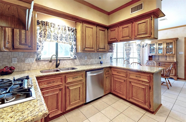 kitchen featuring brown cabinets, a peninsula, stainless steel dishwasher, gas stovetop, and a sink