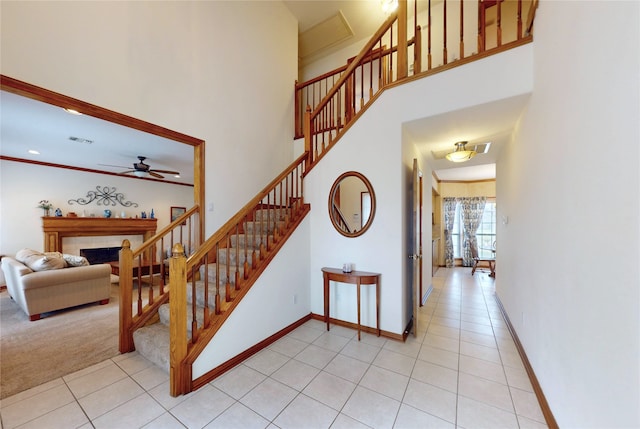 staircase with baseboards, a towering ceiling, visible vents, and tile patterned floors