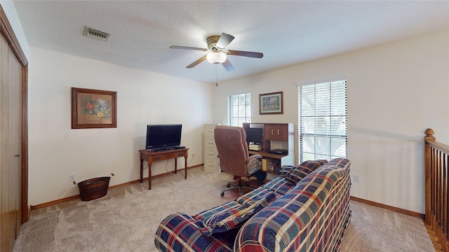 home office with visible vents, a ceiling fan, light carpet, a textured ceiling, and baseboards