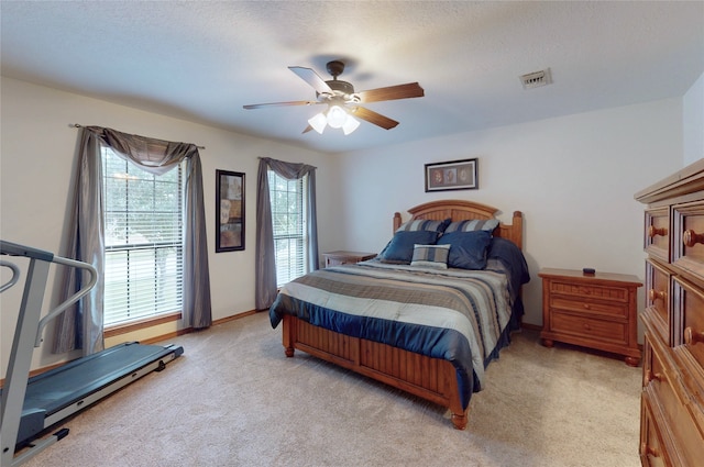 bedroom featuring baseboards, visible vents, a ceiling fan, light colored carpet, and a textured ceiling