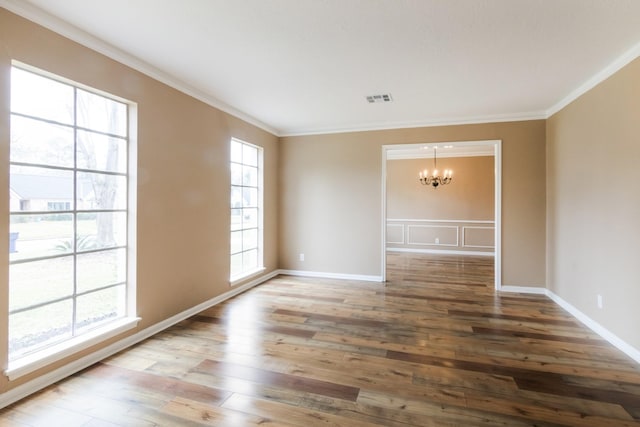 spare room with baseboards, visible vents, wood finished floors, crown molding, and a chandelier