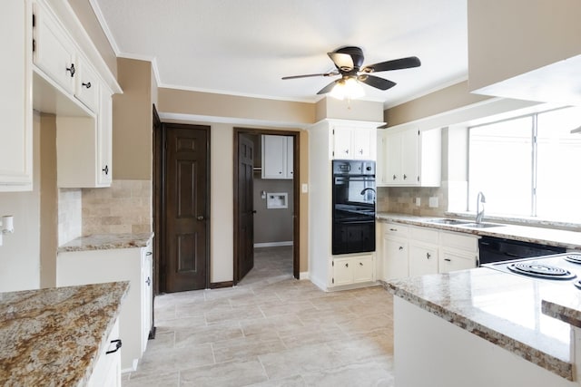 kitchen with light stone counters, white cabinets, a sink, and ornamental molding