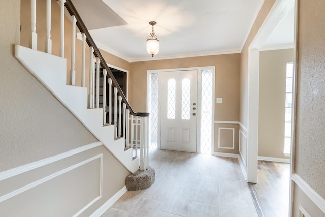 entrance foyer with light tile patterned floors, plenty of natural light, stairs, and crown molding