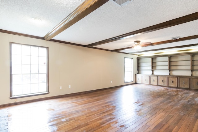 unfurnished living room featuring a textured ceiling, visible vents, beam ceiling, and wood finished floors