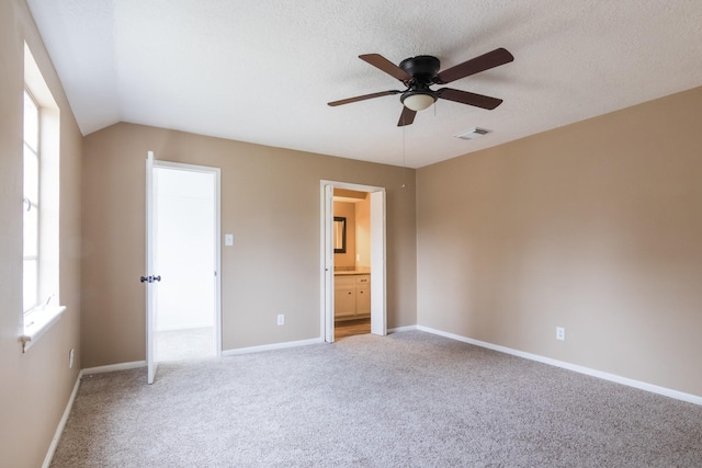 unfurnished bedroom featuring carpet, visible vents, a textured ceiling, ensuite bath, and baseboards