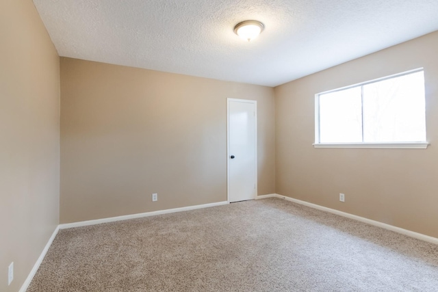 empty room featuring carpet, a textured ceiling, and baseboards